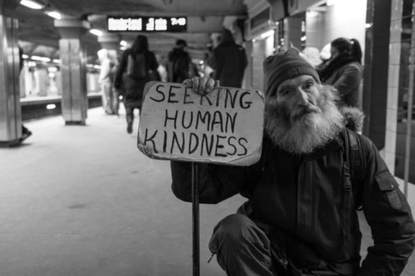 Socijalni fond - Čovjek na kolodvoru s velikom bradom prosi i drži natpis seeking human kindness